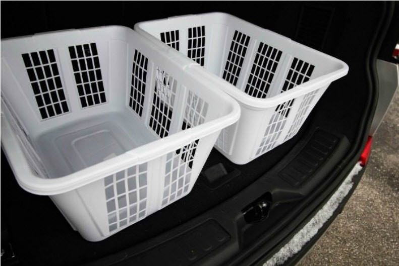 Two white laundry baskets sitting in the trunk of a car