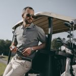 golfer dressed in smart clothes leaning on a golf cart